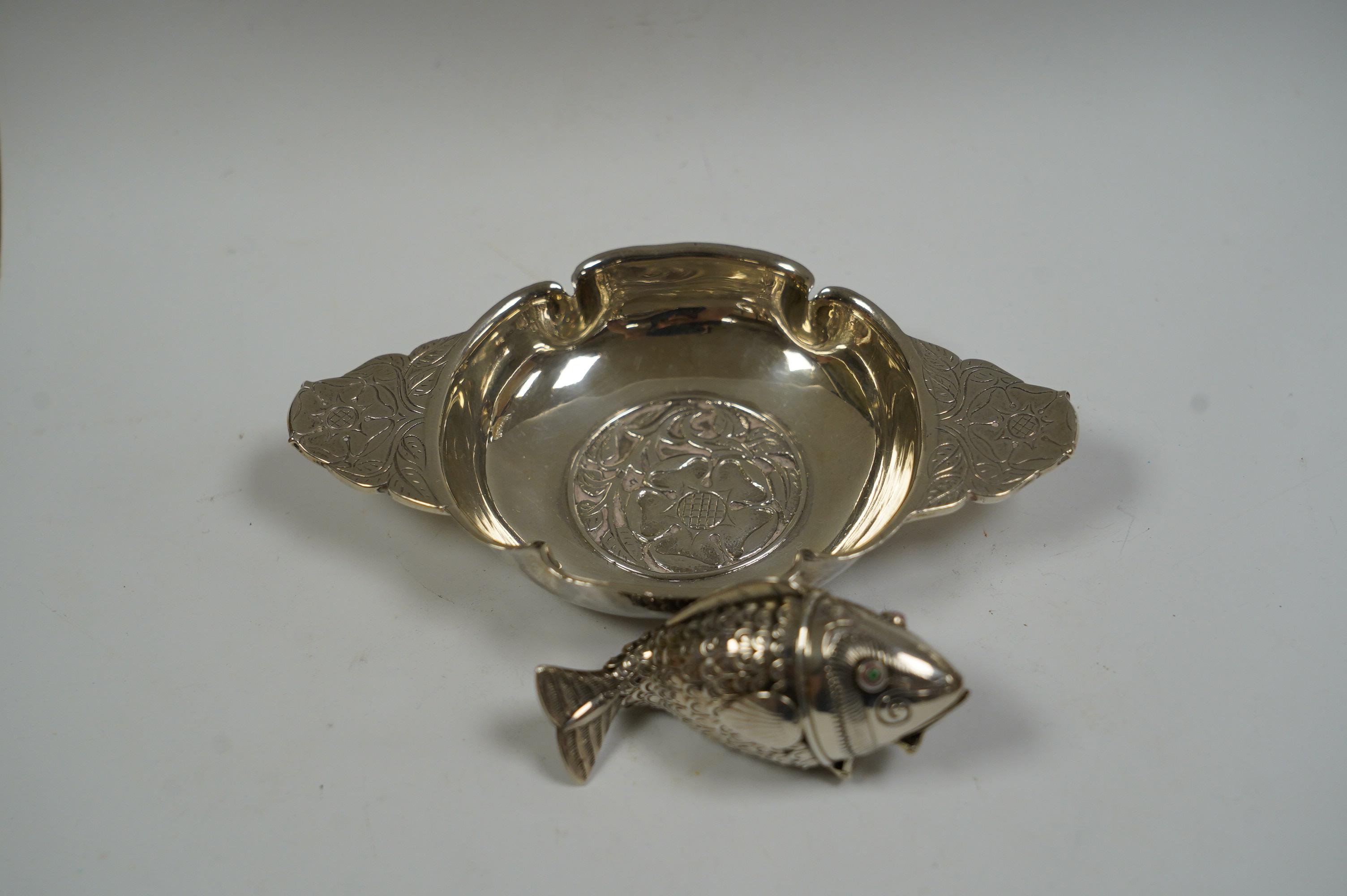 A George V foliate engraved silver quaich by Robert Edgar Stone, London, 1936, 12.2cm, together with a Norwegian 830 standard white metal articulated fish pill box, 60mm. Condition - fair to good